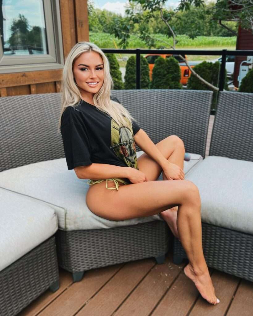 Claudianne Godbout in black t-shirt with panty while sitting on sofa and smiling towards camera