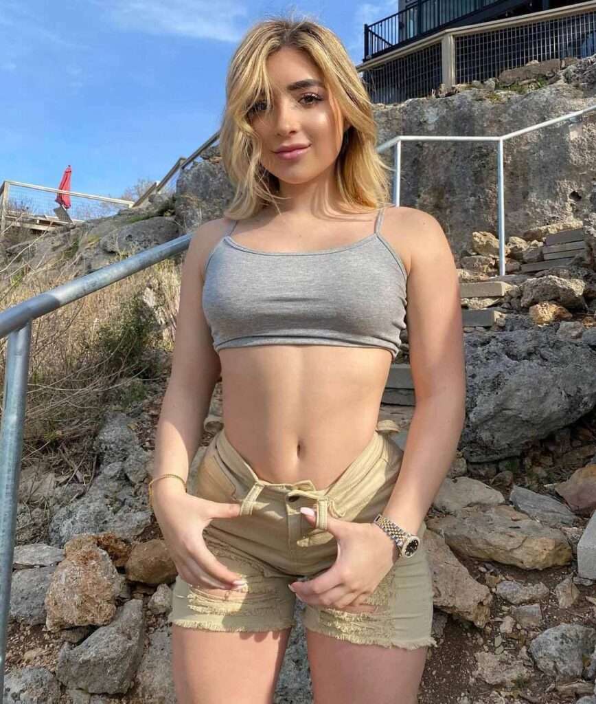 Faith lianne in a grey crop top and brown shorts while smiling towards camera