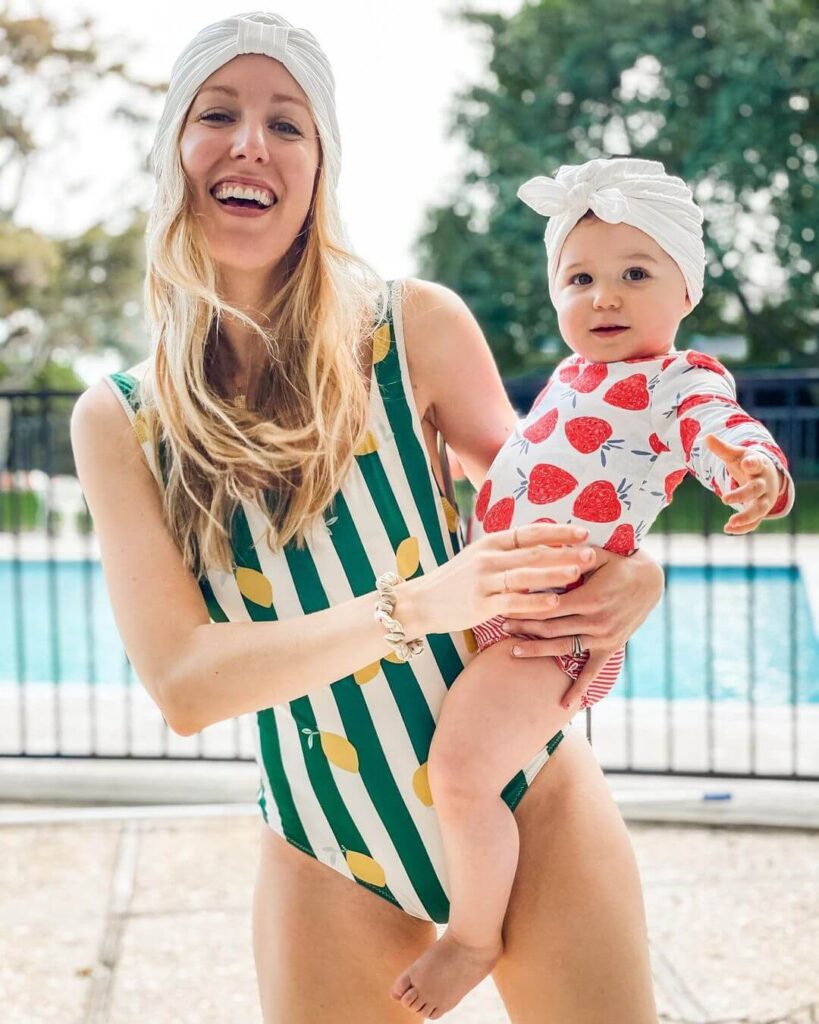 Liz Teich wearing a branded carve swimwear while  holding her daughter