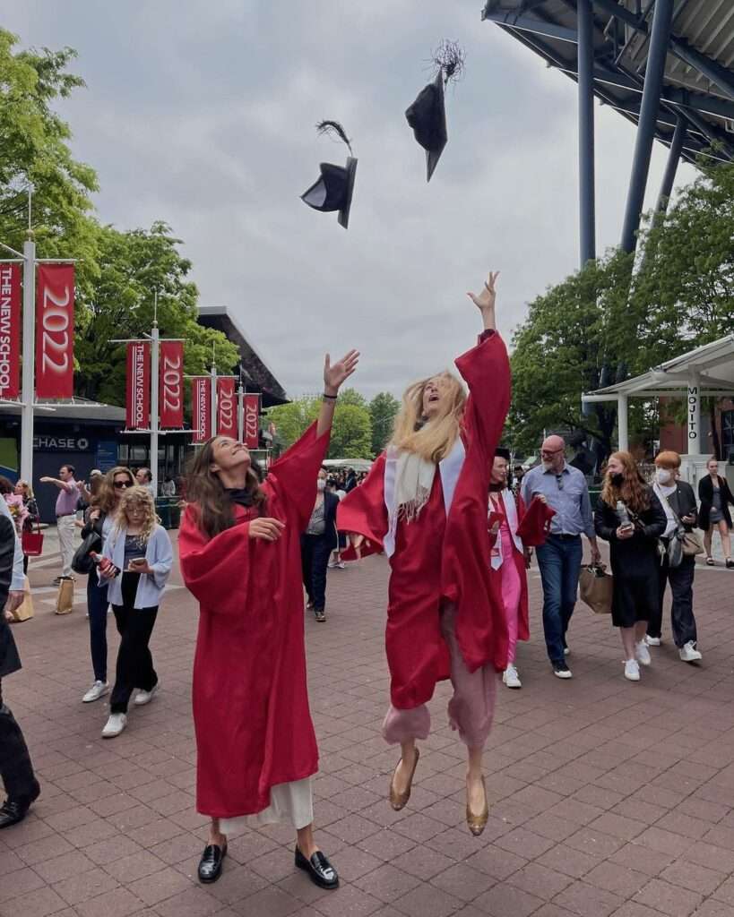 Rocio Crusset in a convocation costume with her friend while throwing their caps in the air 