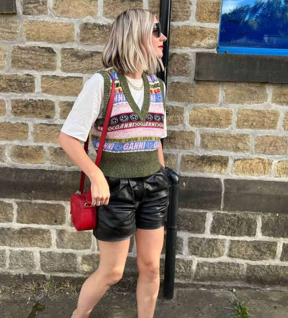 Sarah Hughes in  a reformation mini dress pair with red bag and goggles while giving a side pose for taking a picture