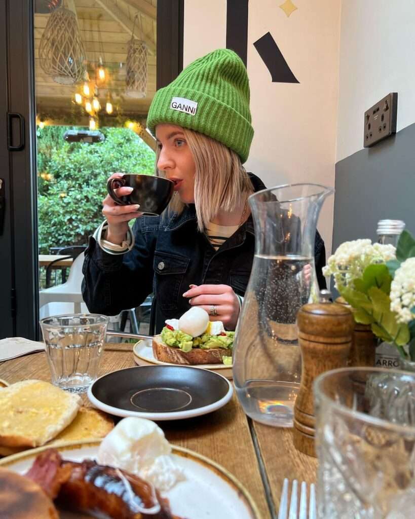 Sarah Hughes in a black denim jacket with a green cap while eating her breakfast 