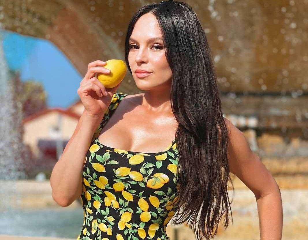 Lola Astanova in a reformation style dress while holding mango in her hand