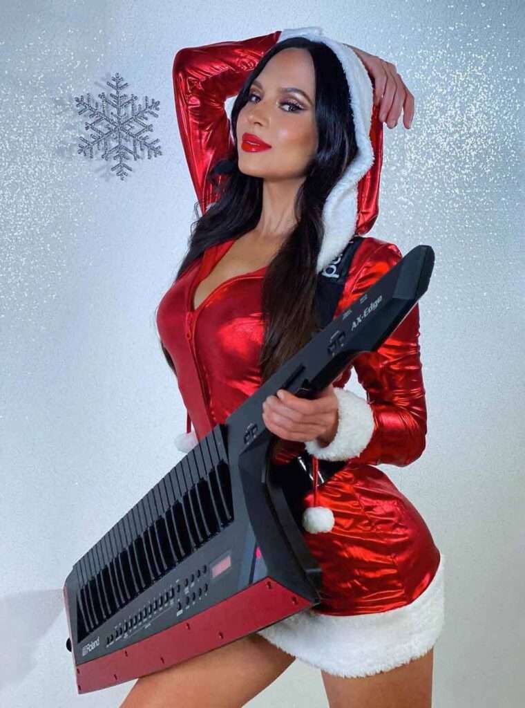 Lola Astanova in a santa claus costume while holding a piano in her hand