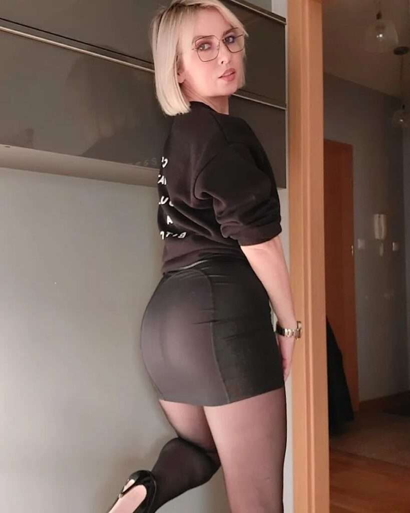 Alexandra in a black sweat shirt with a matchinh skirt and black pantyhose while showing her back towards camera