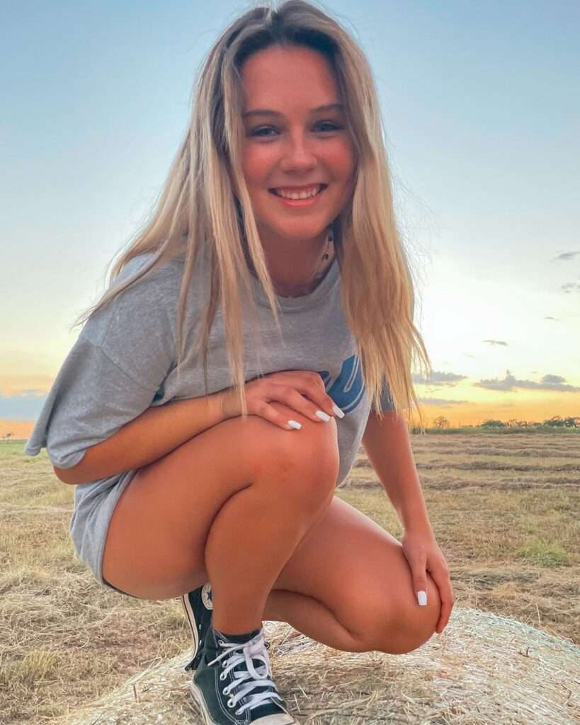 Alyssa McBride in a grey t-shirt with panty and sneakers while smiling towards camera