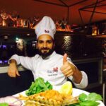 Faruk-Gezen wearinga chef costume while taking a picture with his delicious sea food