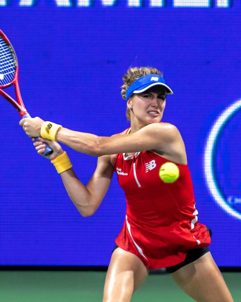 Genie Bouchard in the red tennis costume while hitting the ball