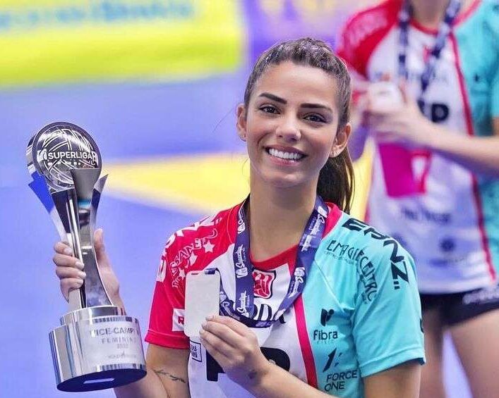 Keyt Alves Ramalho in the volleyball costume while showing her trophy and medal
