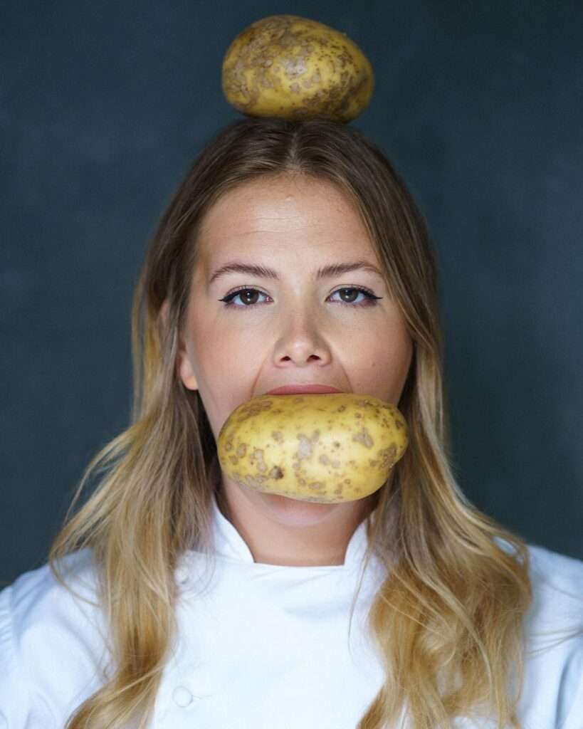 Poppy Cook is dressed as a chef and has a potato on her head and in her month.