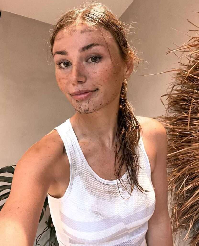 Puck-Moonen in a white tank top with messy face while taking a selfie