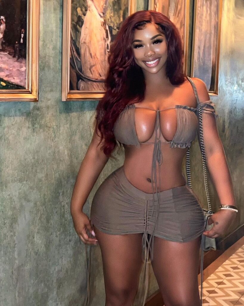 Ravie Loso is standing in a restaurant showing her clothing with a killer smile.