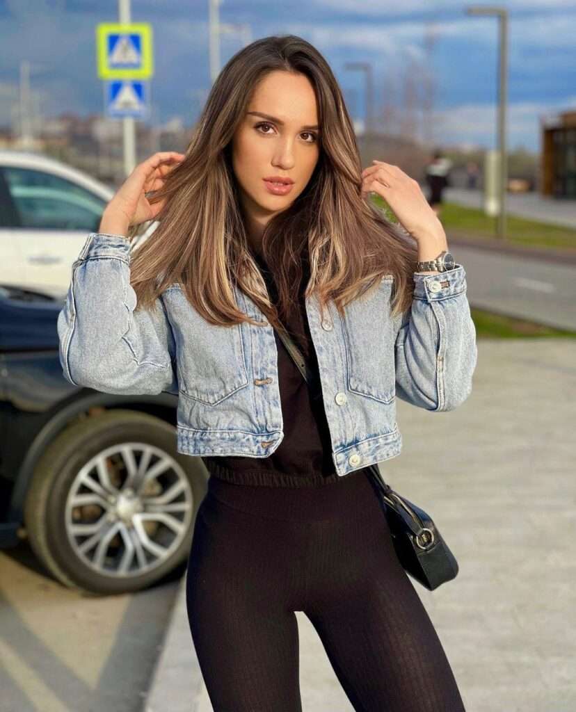Yana Vasileva in the black top pair with black leggings and denim jacket while poses for a picture