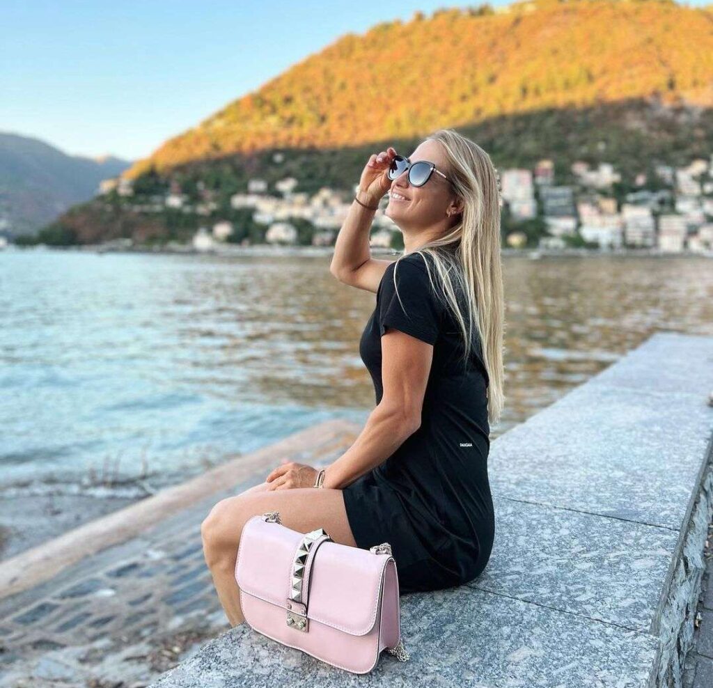 Yulia Putintseva in the black outfit with pink bag while sitting at the bank of river