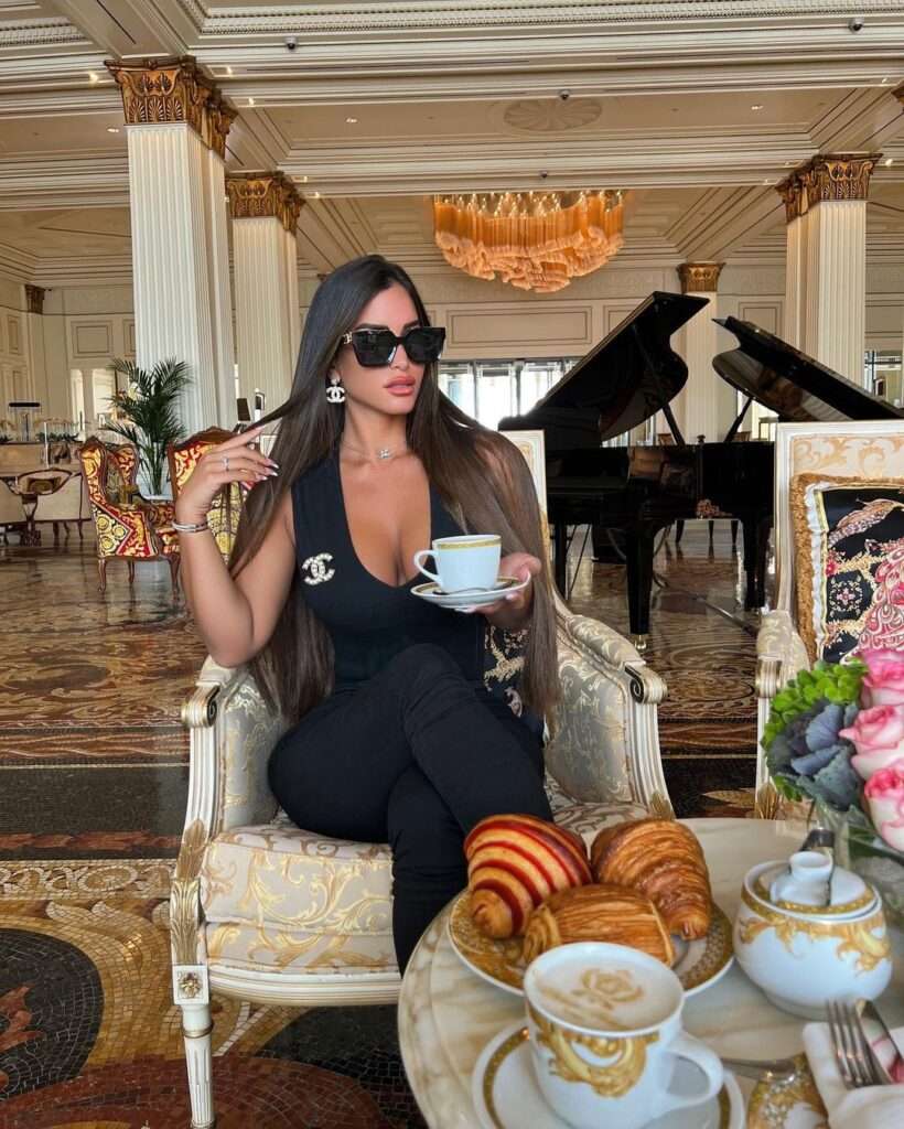 avital cohen in a black stunning outfit while enjoying her coffee with bakery items