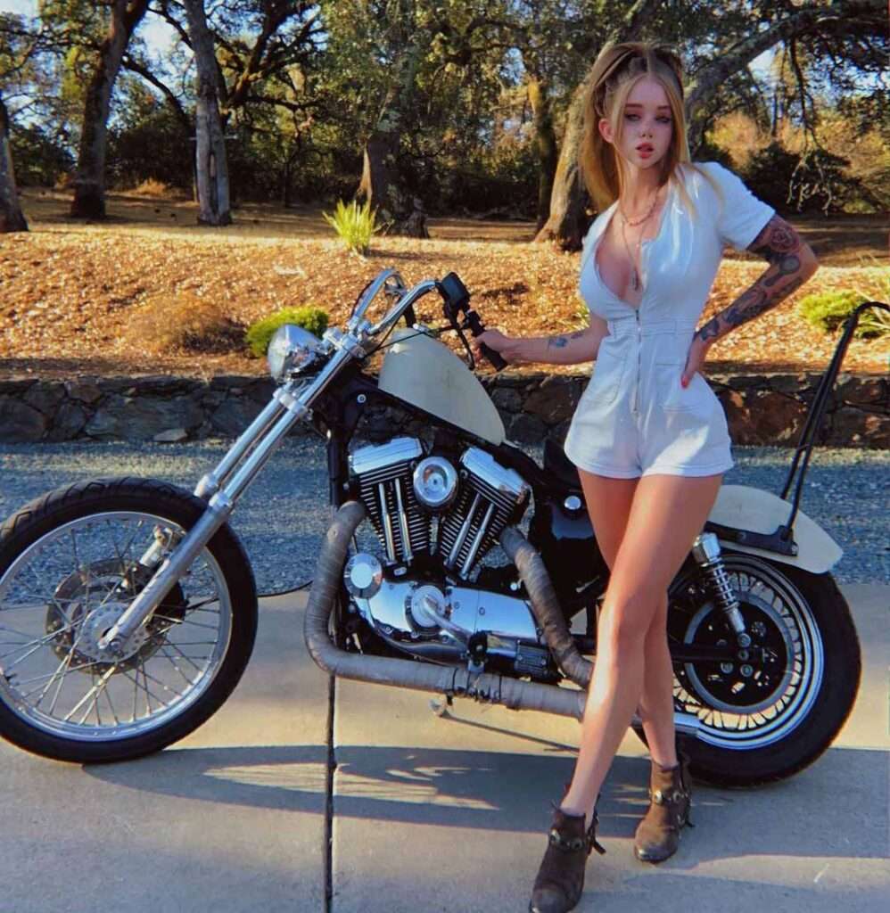 coconut kitty in a white sexy outfit while taking picture with her motorbike