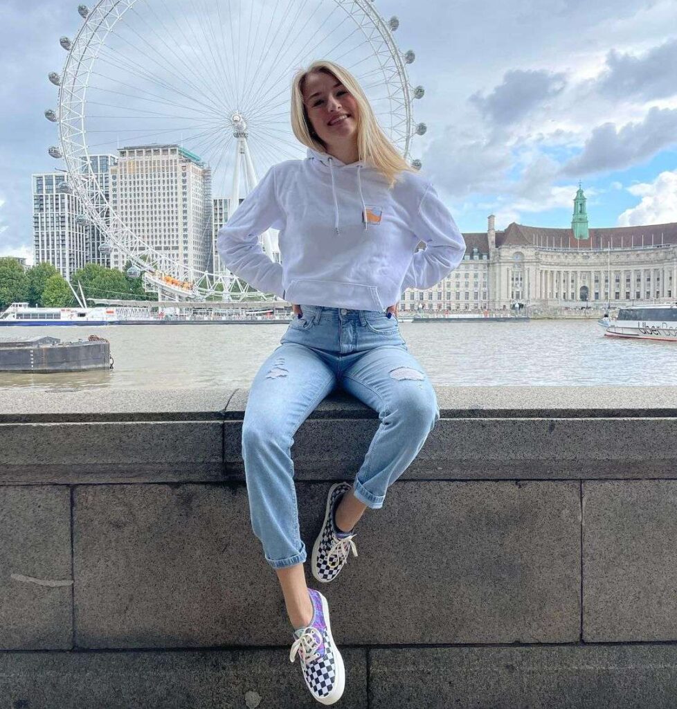 Änna Sophie wearing a white hoodie with denim jeans while smiling for taking a picture