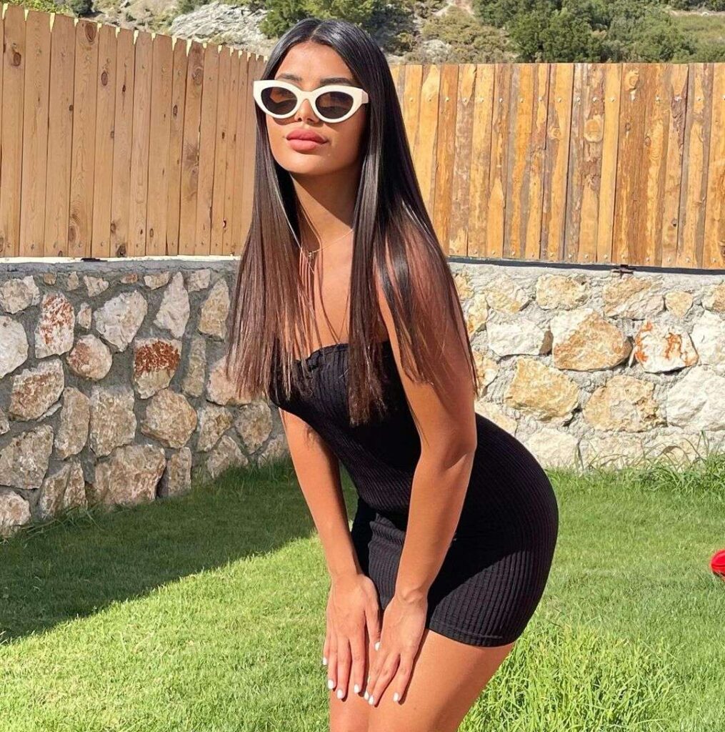 Bahar Dior in the black off shoulder bodycon pair with sun glasses while taking a sun kissed picture