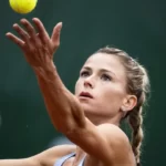 Camila Giorgi in a sky blue tank top while catching the tennis ball