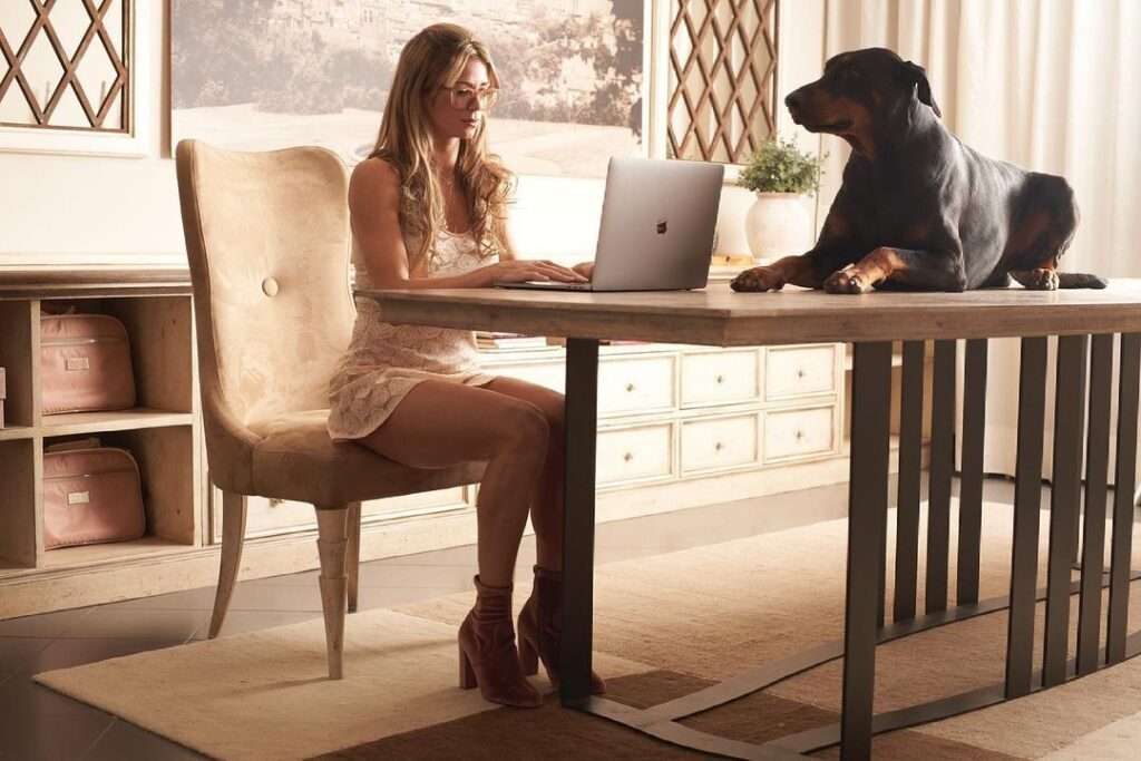 Camila Giorgi is working on laptop while wearing a sexy top and her pet is sitting on the table