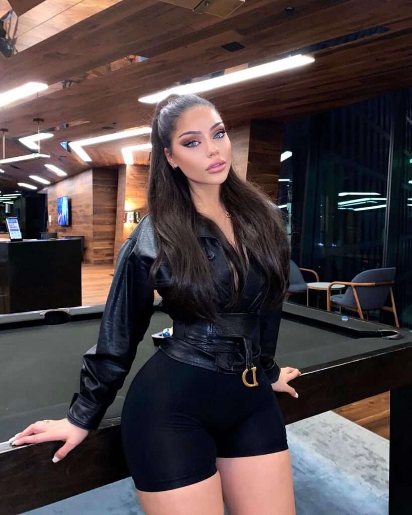 Dina Khalil is standing in a snooker club while wearing a black Fashion Nova jacket with black shorts.