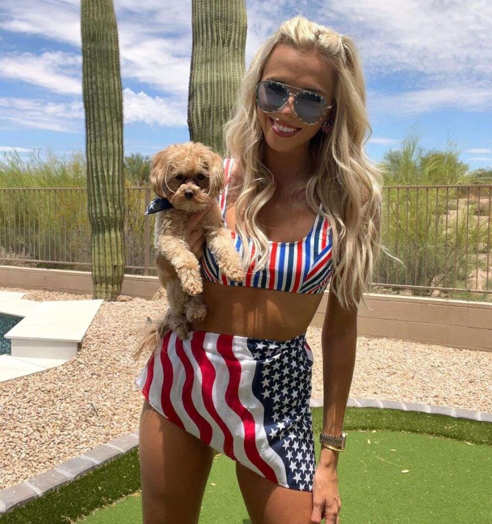 Elise Lobb Dzingel in a crop tank top with mini skirt while holding her pup and smiling towards camera