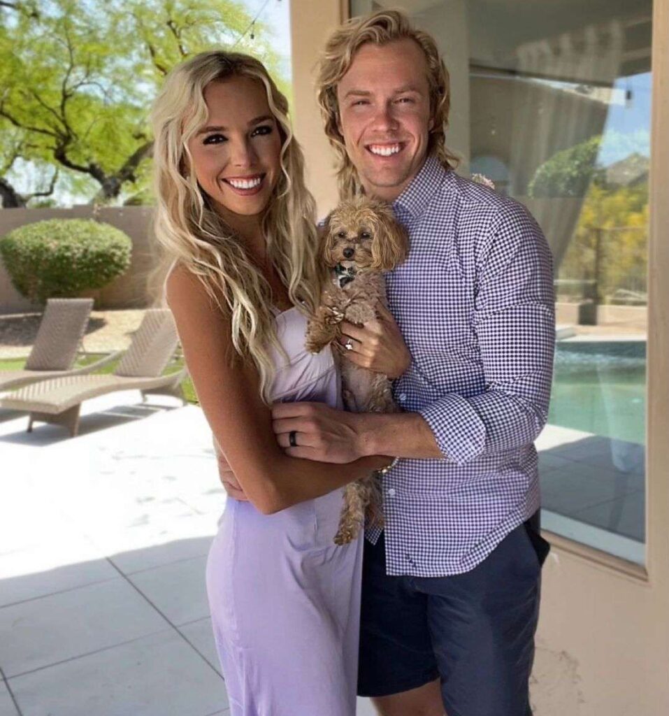 Elise Lobb Dzingel is taking a picture with her husband while holding her pup