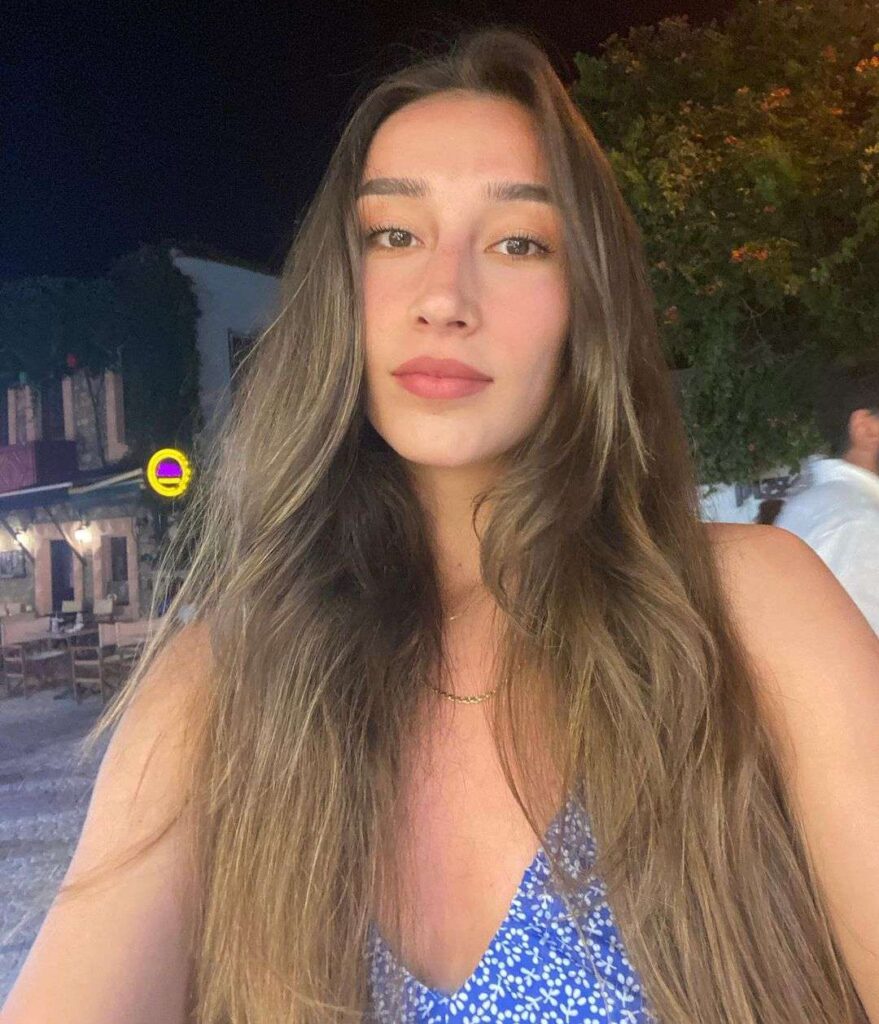 Hande Baladin in a floral print blue top while taking a picture