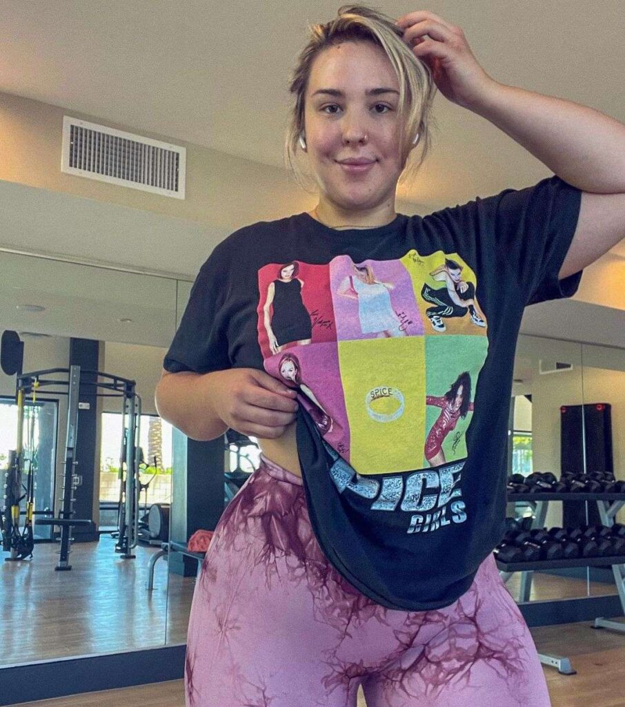 nixxdee wearing a black printed t-shirt with printed leggings while taking a picture in the gym