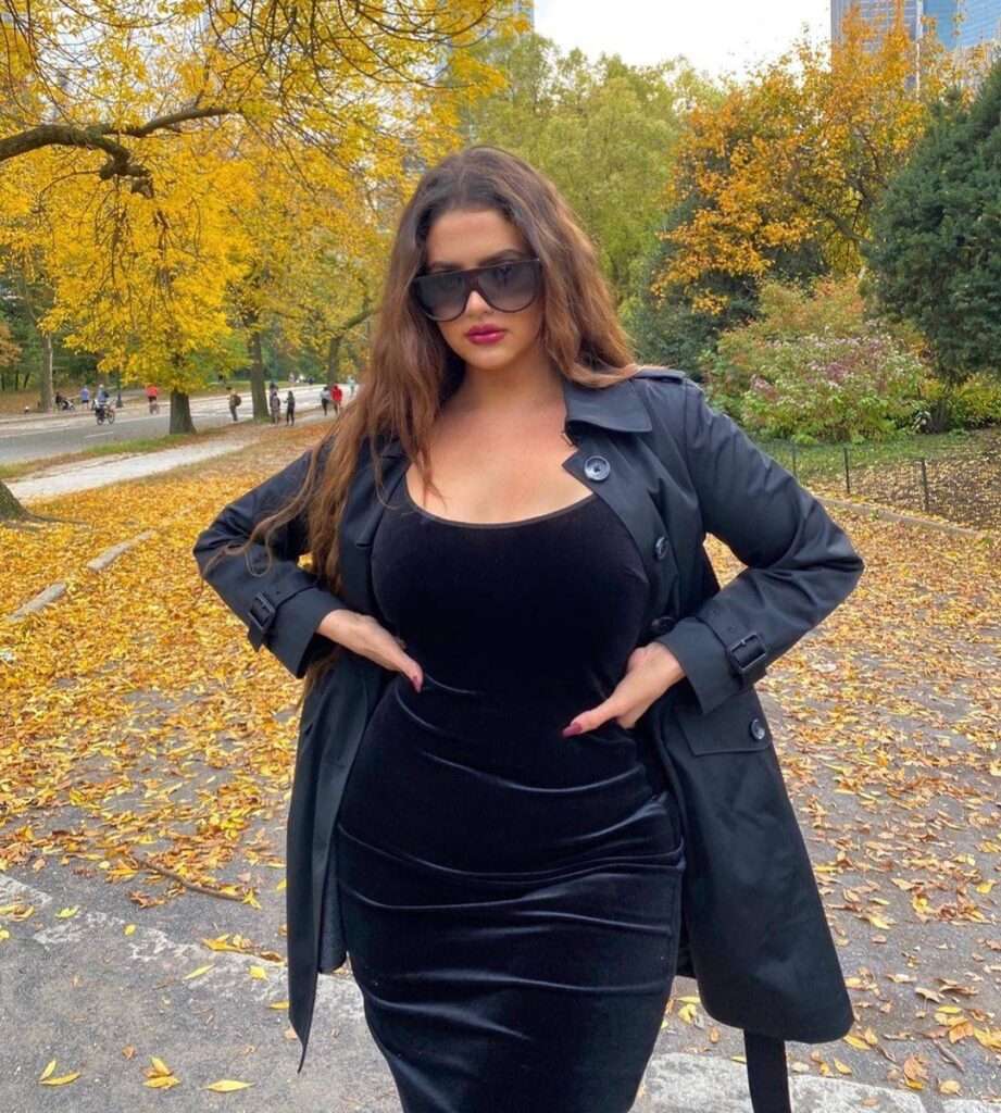 Olenia Caymares in a black velvet bodycon pair with black over coat and goggles while poses for a photo