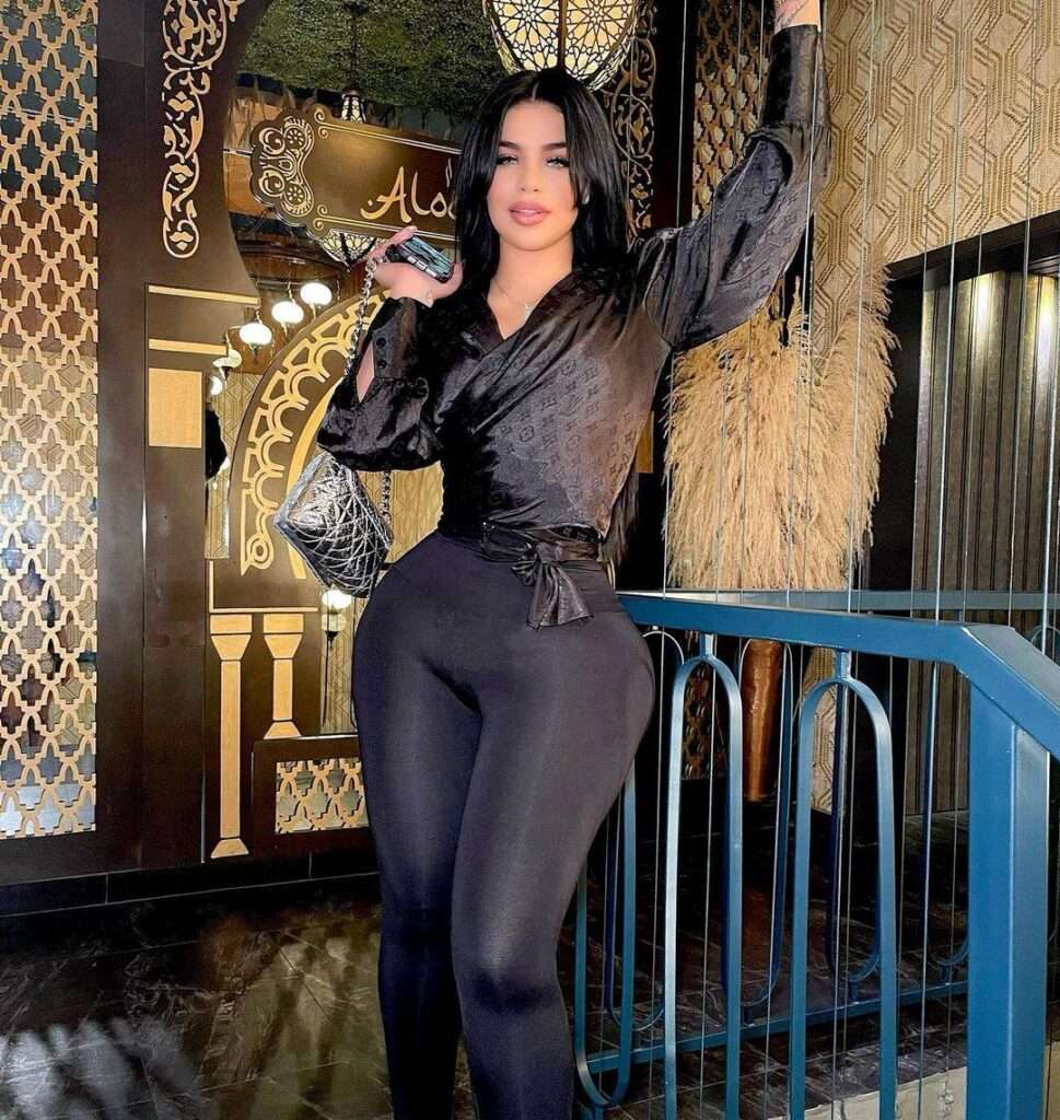 Renattadr in a black silky shirt with matching leggings while poses for a photo