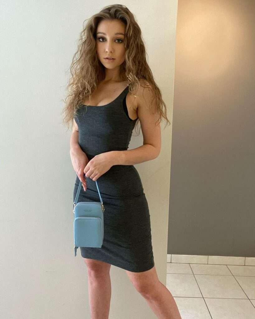 Shirley in the black bodycon with blue handbag while poses for a photo
