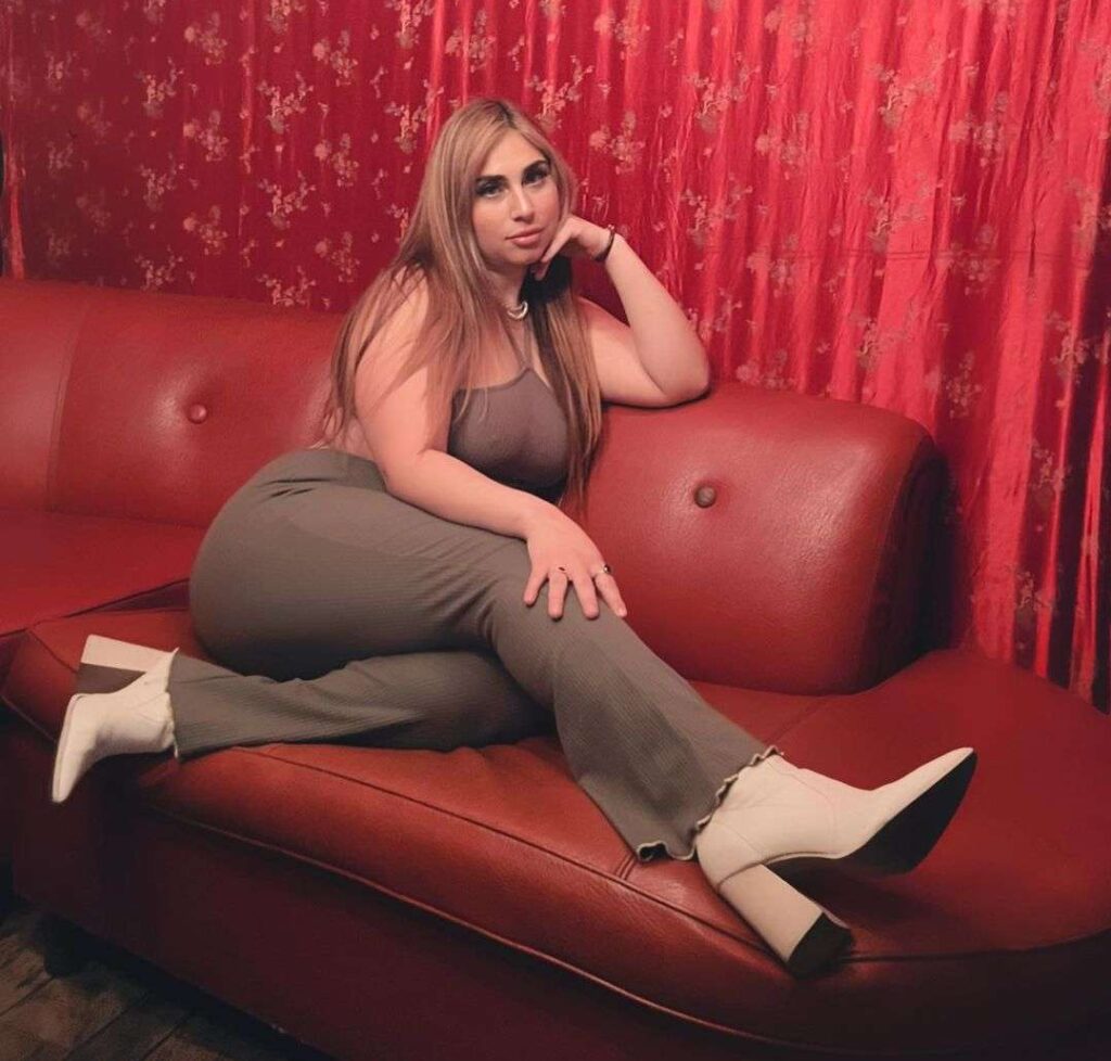 TherealNetti is sitting on the sofa and poses for a photo while wearing a brown outfit with creamy brown heels