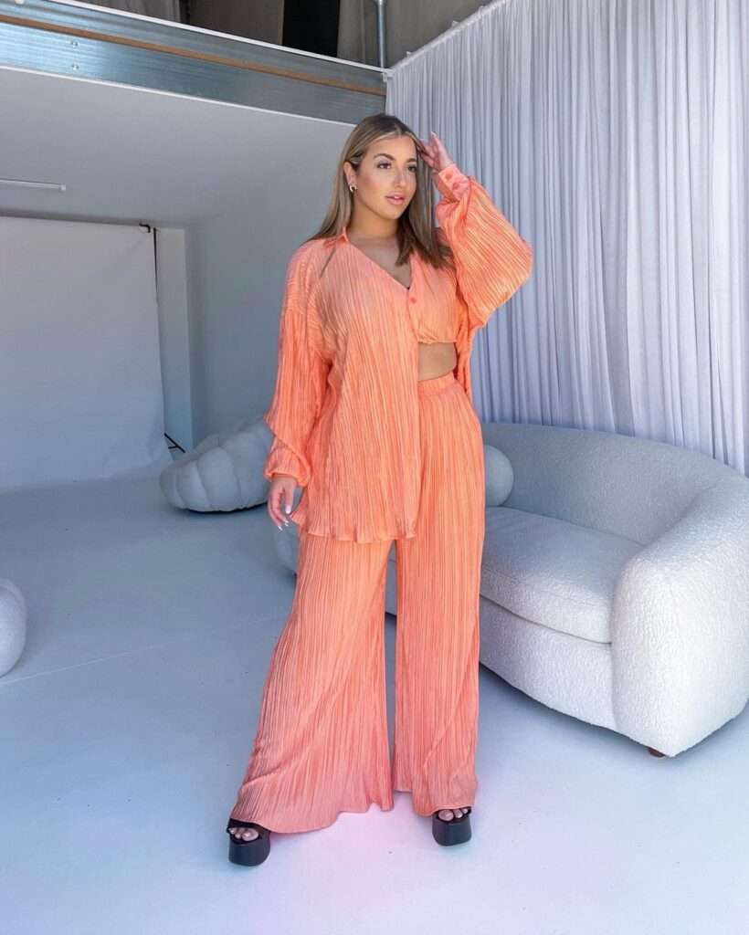 Tiana Sala in a stunning orange outfit with black heals while poses for a photo
