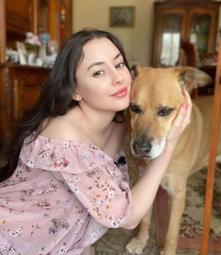 Fiona Allison in a floral print top while taking a picture with her pet dog