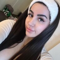 Amelia Curvy taking a close-up selfie indoors, wearing a white fuzzy headband and long straight dark hair.