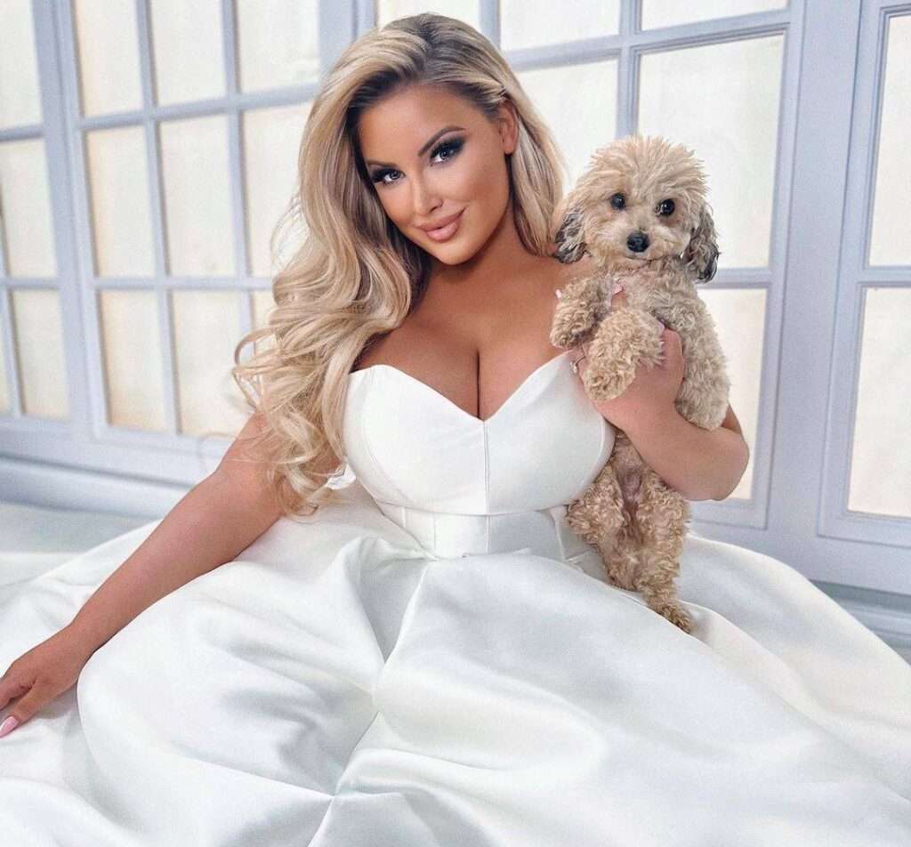 Ashley Alexiss in a sexy and beautiful dress while holding her pet and looking towards camera