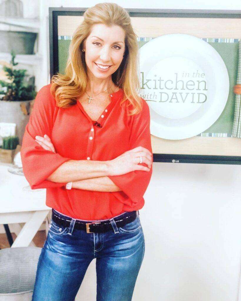 Cook With Shereen is just posing for a picture while wearing a red check shirt with denim pant.