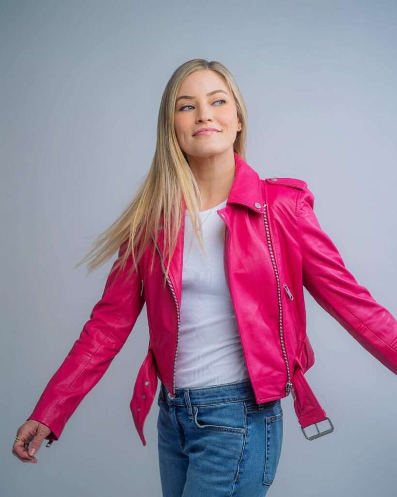 iJustine is looking beautiful in pink jacket and blue denim pant looking happy.