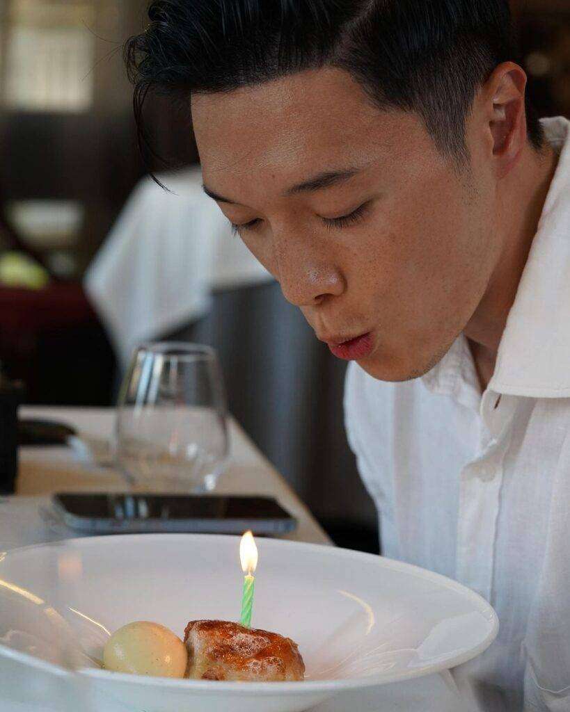 Lennard Yeong is celebrating his 34th birthday at a restaurant and blowing the candle.