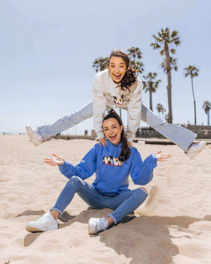 Merrell Twins are sitting at beach and there they are posing for a picture looking cute.
