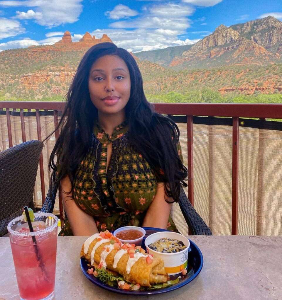 Osha Waiters is looking towards camera while eating her breakfast in a sleeveless top