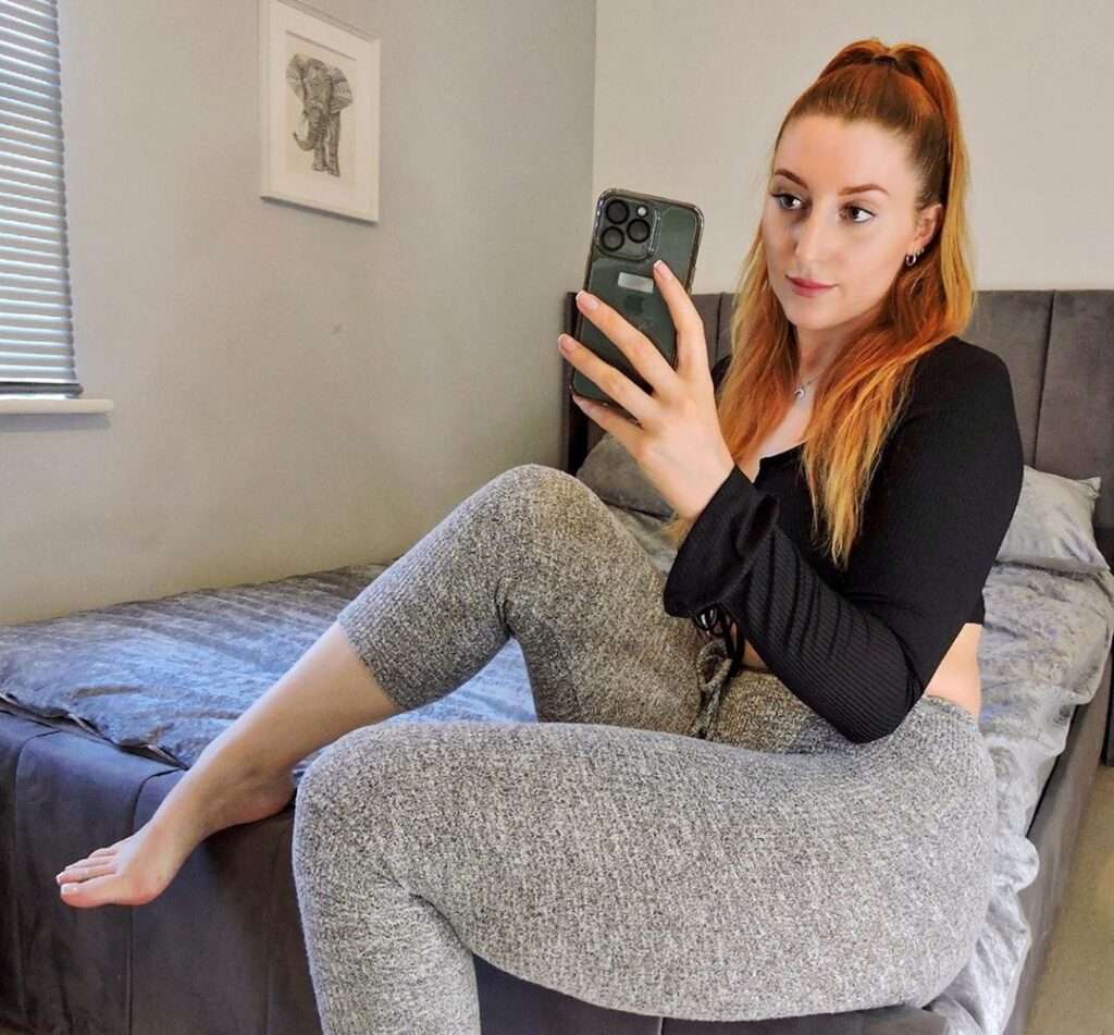 Emily Stallabrass in the full sleeves black crop top pair with grey leggings while taking picture in the front of mirror