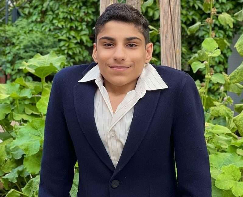 Ghanim Al-Muftah is in three piece suit and is looking happy and is posing for a picture.