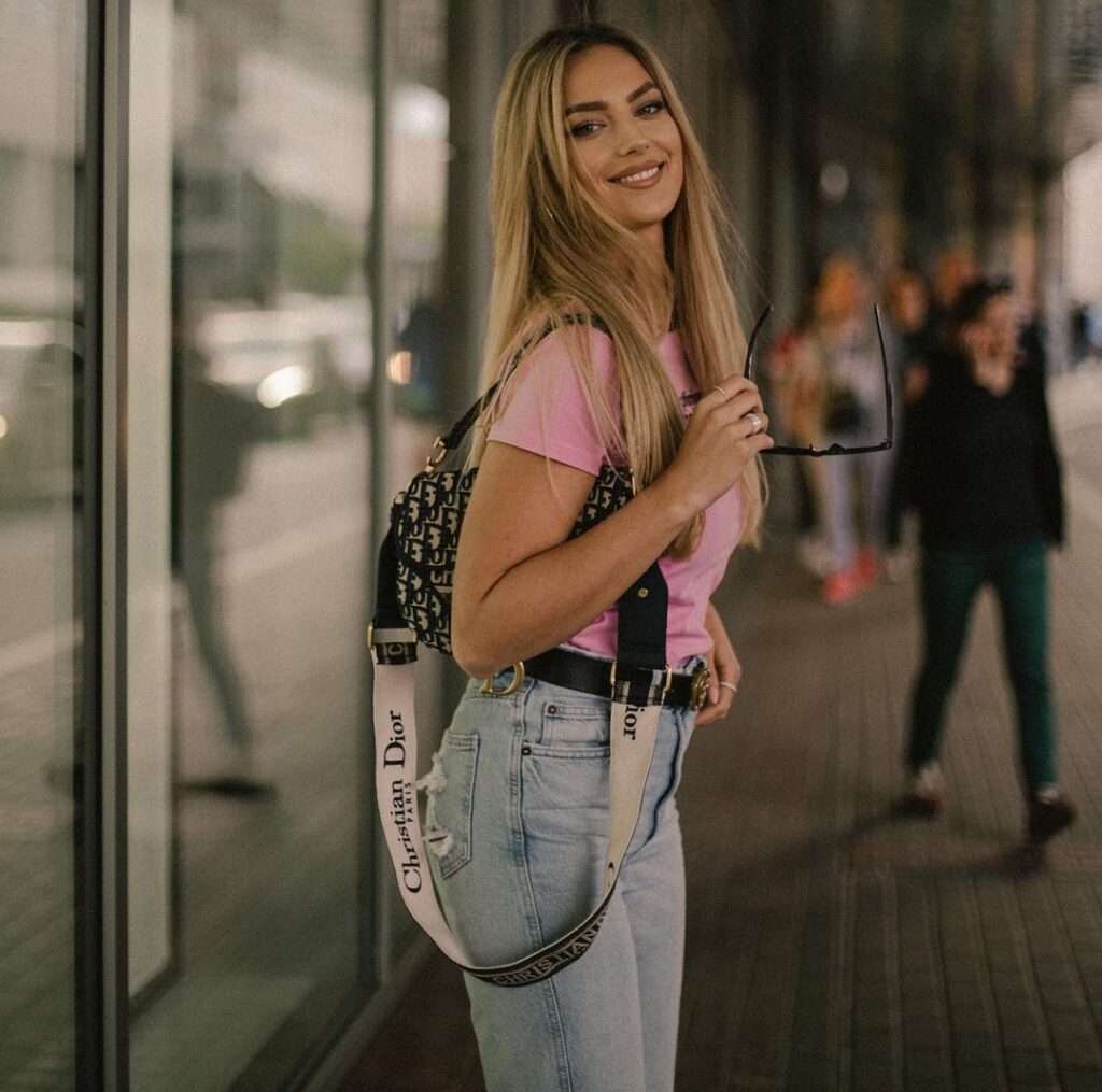 Klaudia Wonatowska in the pink t-shirt pair with blue jeans and bag while smiling towards camera