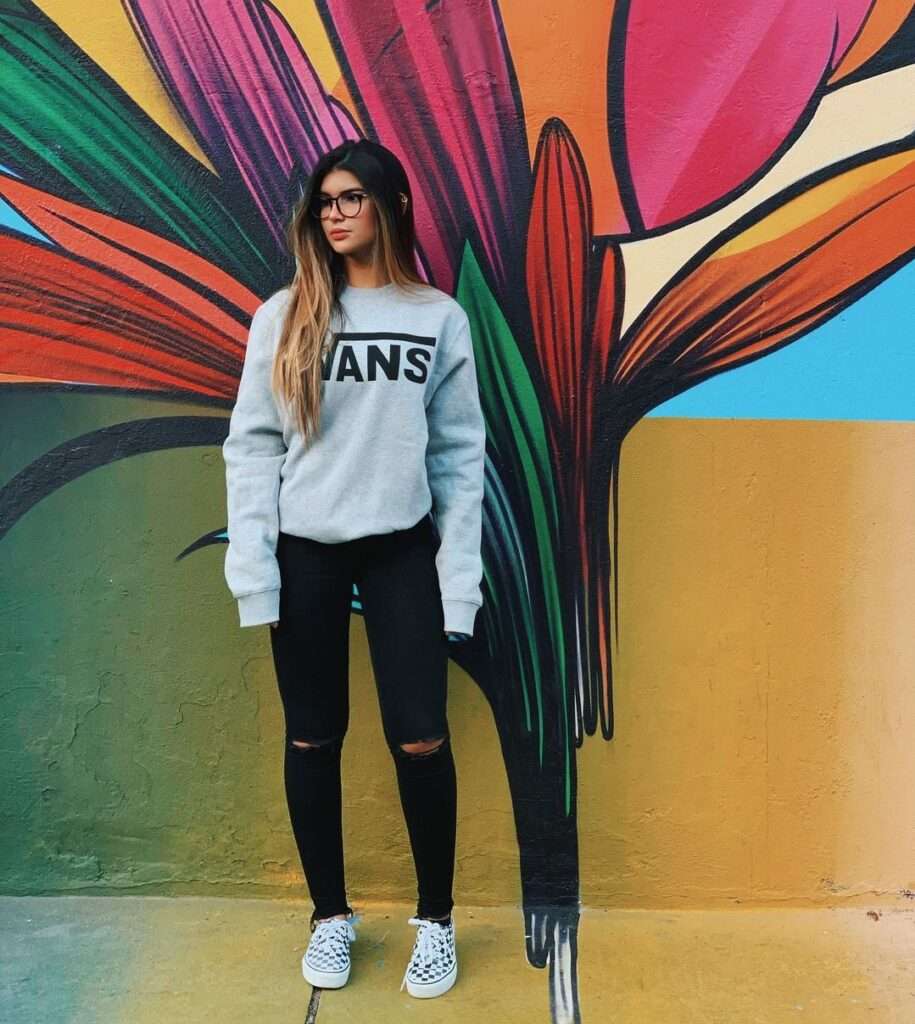 Lara Scoa in the blue sweatshirt pair with black jeans and sneakers while taking a picture