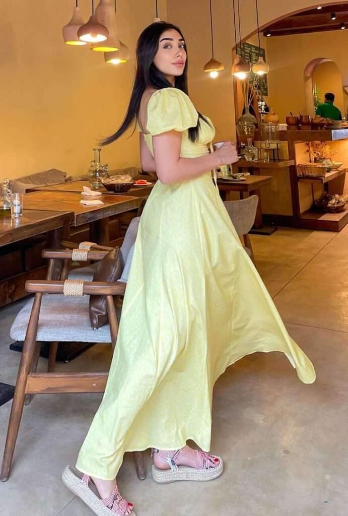 Linda Harb is in long frock and is standing in a restaurant looking beautiful.