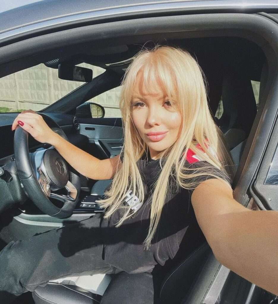 Maria Lapulina in the black t-shirt with black pant while taking picture from a car