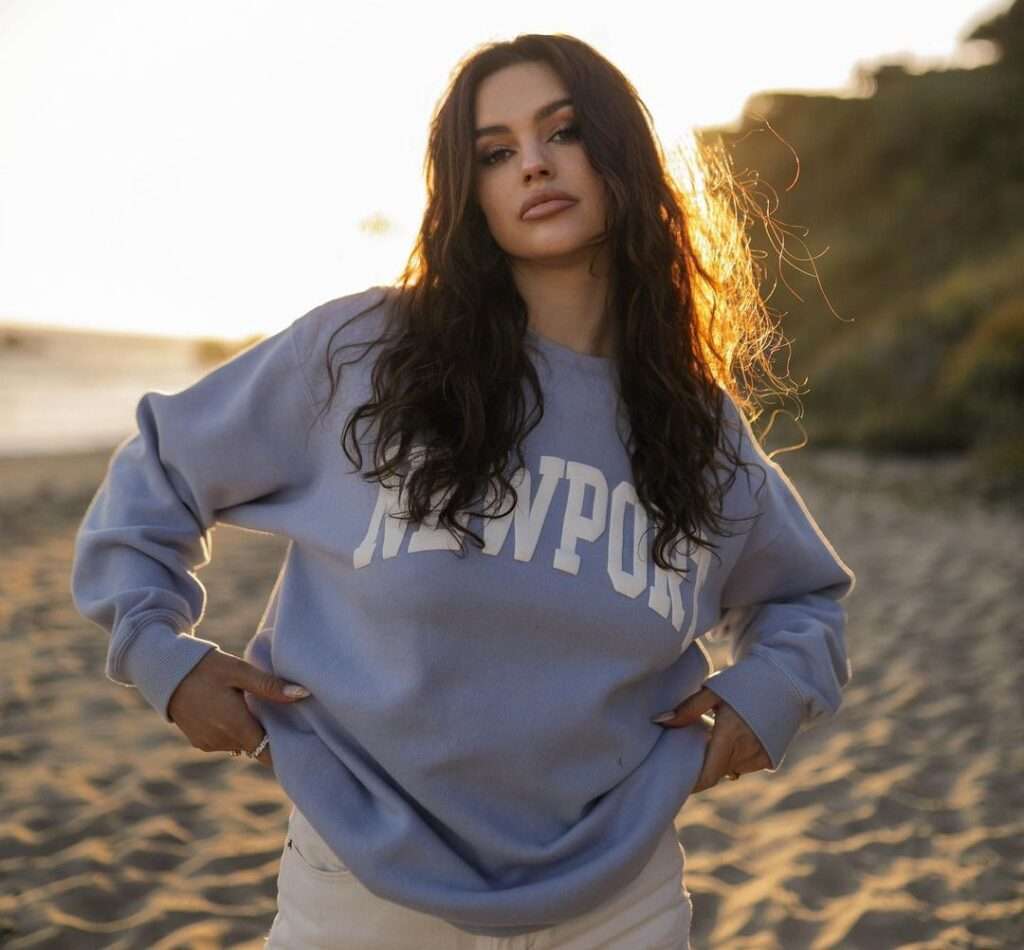 Maribel Sancia Todt is poses for a photograph at the sea side while wearing a grey sweatshirt with off-white pants