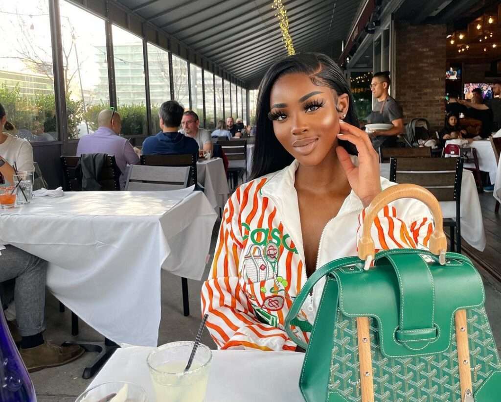 Newyork Taylor in the funky front zip shirt pair with green bag while smiling towards camera in a cafe